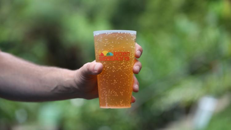Hand holding Eden Sessions cup filled with cider