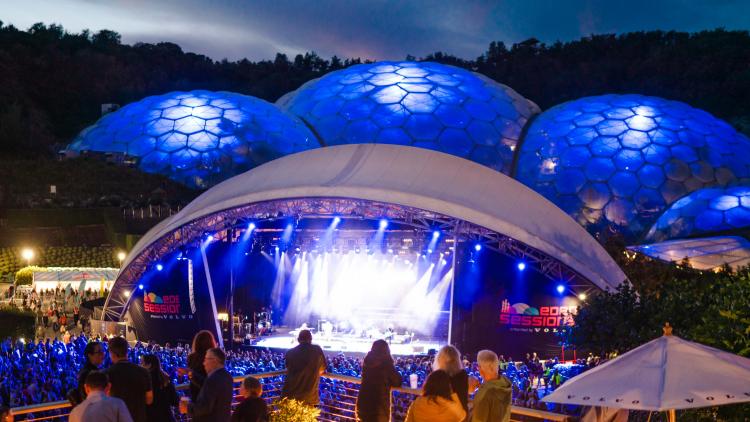 People watching gig from VIP platform with a view of the stage and lit up Biomes